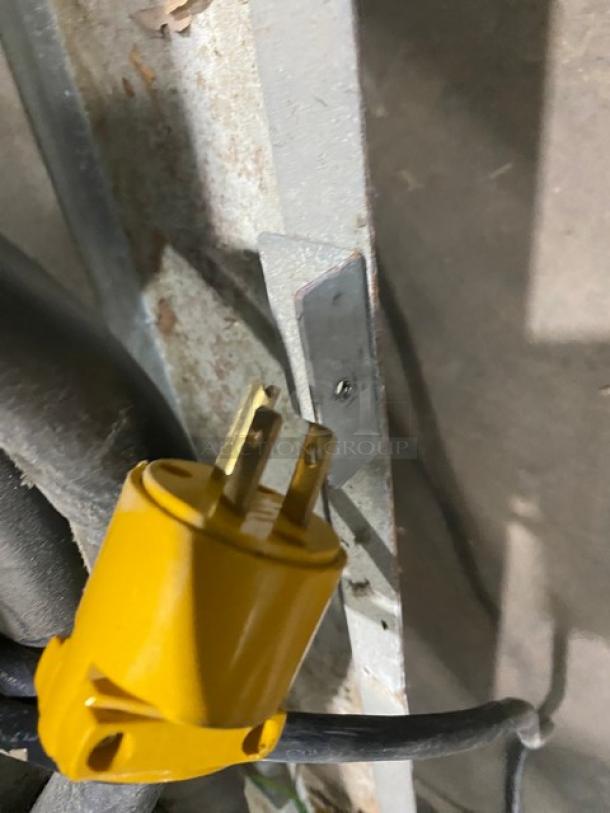 Yellow electrical plug on a cable, shown next to a metal surface with screws, for Avantco commercial refrigerator, Model CFD-2RR.