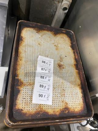 Commercial perforated sheet pan, used condition with rust and patina. Includes a printed quantity label for auction referencing.
