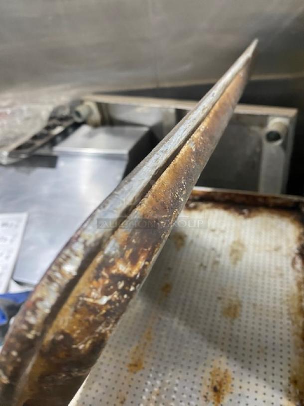 Commercial perforated sheet pan, used condition with visible rust and wear. Suitable for baking, enhances heat circulation.