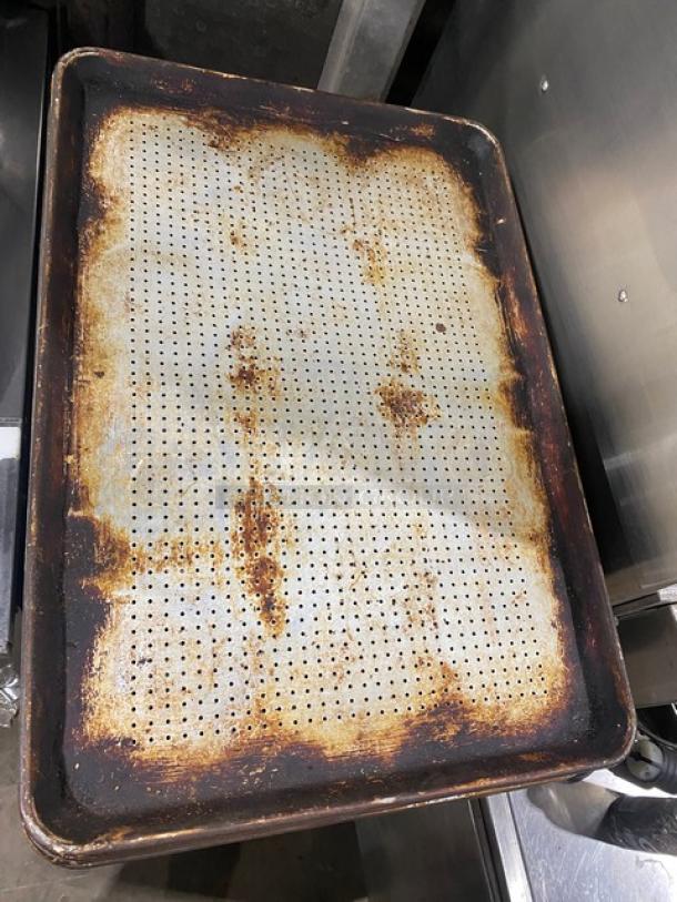 Commercial perforated sheet pan with rust, used condition, rectangular shape, metal material. Ideal for baking.