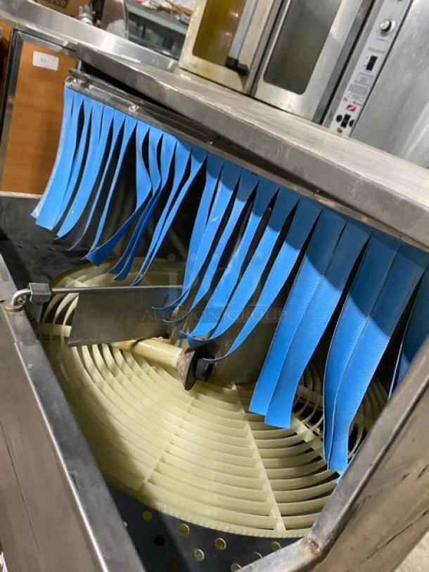 CMA GL-C stainless steel undercounter carousel bar dishwasher with blue flaps and visible interior rotor. On legs.