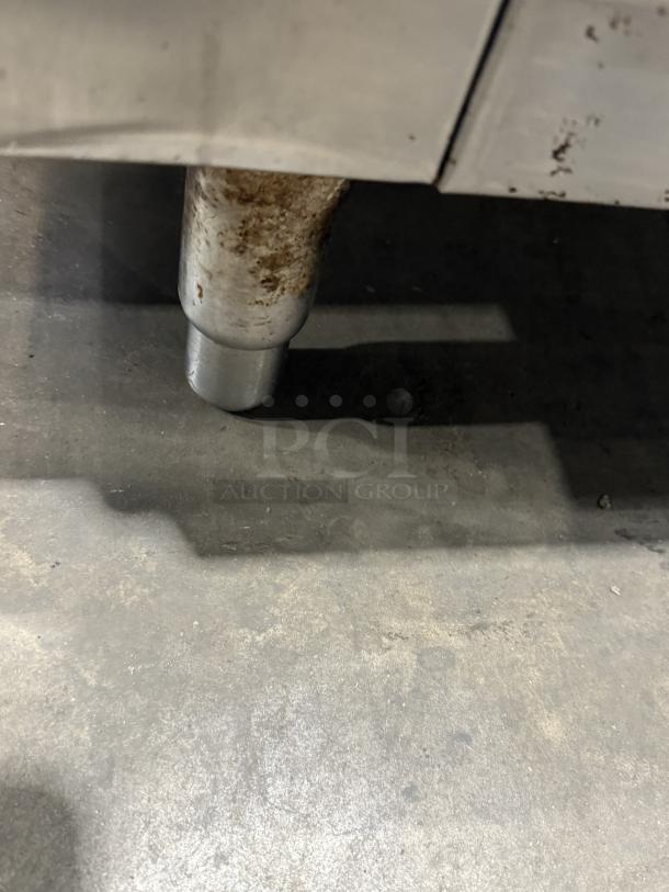 Traulsen 4 split door reach-in cooler leg on concrete floor. Chrome rack shelving, 115V, 1 phase. Visible rust and wear.