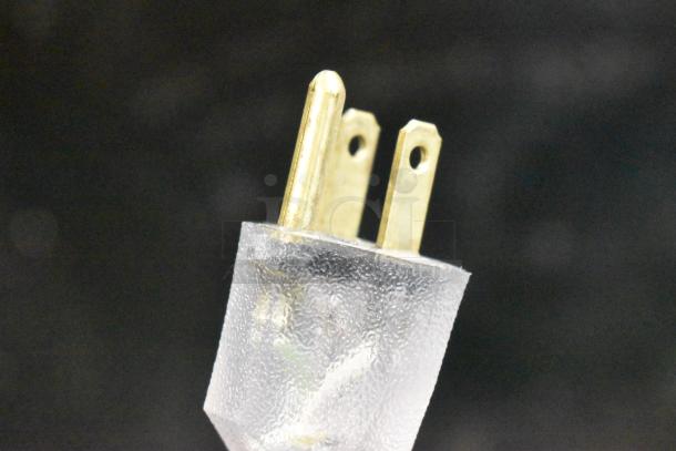 Three-prong electrical plug with transparent protective covering.