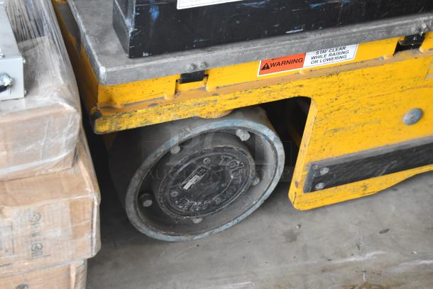 Bil Jax ESP-19 Haulotte industrial man lift, 450 lb capacity, yellow with visible warning label, sturdy wheel.