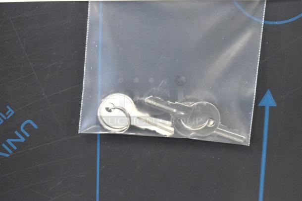 A small plastic bag containing two metal keys on a ring, placed on a dark background.