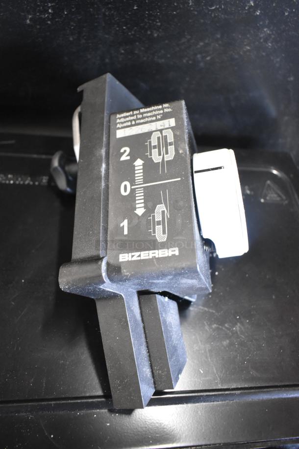 Bizerba SE 12 D US meat slicer blade sharpener component. Shows adjustment markings and Bizerba branding.