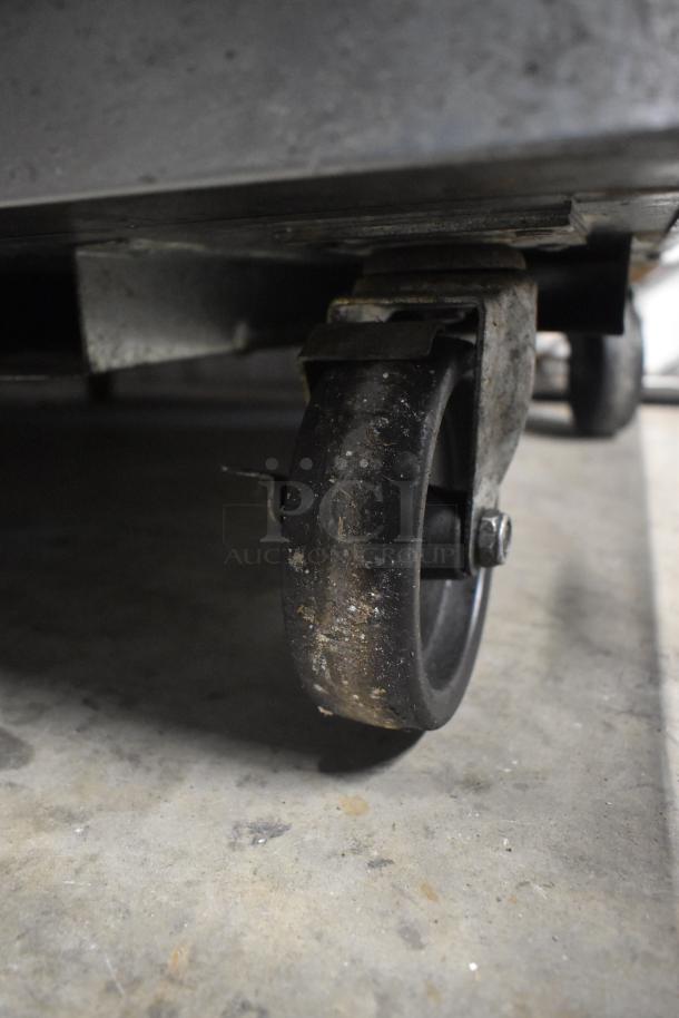 Close-up of a commercial caster from a 2016 True TUC-27F-D-2-HC undercounter freezer, showing wear and dirt.