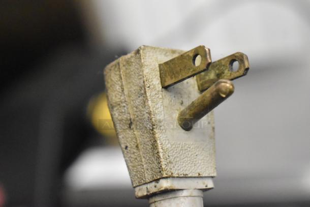 Close-up of a worn electrical plug, showing signs of age and patina, part of a 2016 True TUC-27F-D-2-HC freezer.