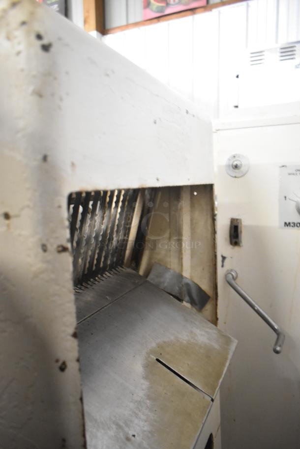 Commercial floor-style bread loaf slicer, metal blades visible. Operates on 115 volts, 1 phase. Used condition.