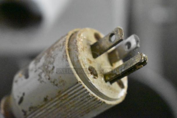 Close-up of a rusted, three-pronged plug from a commercial floor-style bread loaf slicer, 115 volts, 1 phase.