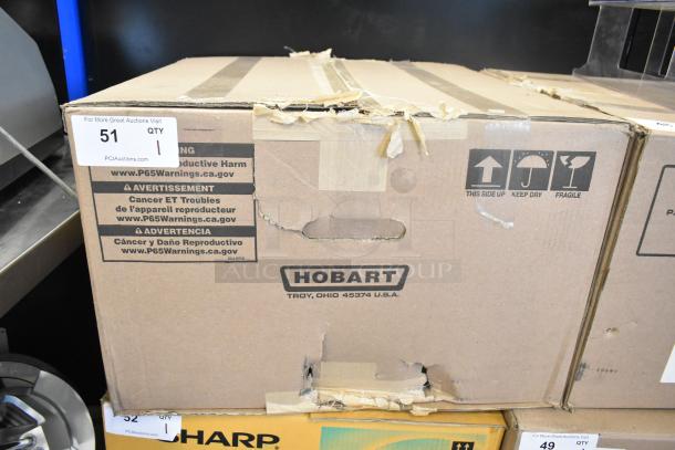 Cardboard box for Hobart HTi-7LH scale, showing wear. Labels warn of reproductive harm. Box marked "Hobart, Troy, Ohio USA."