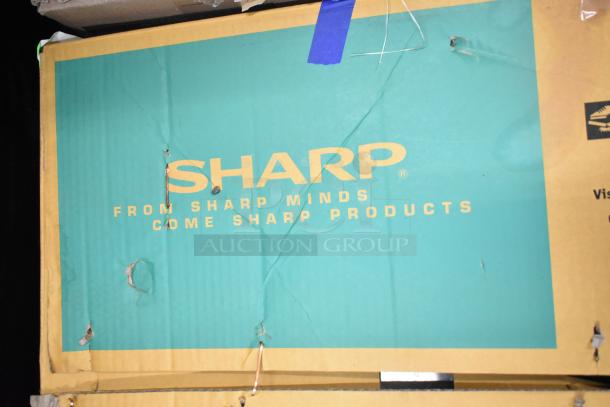 Cardboard packaging for Sharp R-21LVF commercial microwave oven, visible wear, includes branding and slogans.