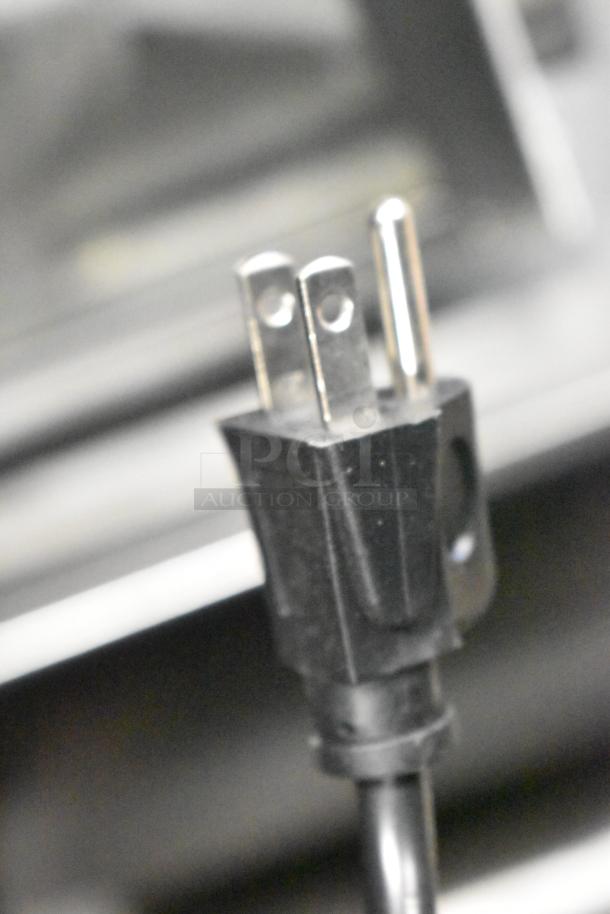Close-up of a three-prong plug for the Proctor Silex PS-P70T20AL-V1B Countertop Microwave Oven, black cord visible.