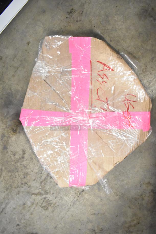 Cardboard-wrapped item, secured with pink tape and plastic wrap, placed on concrete floor. Markings include "A54" and "U51."