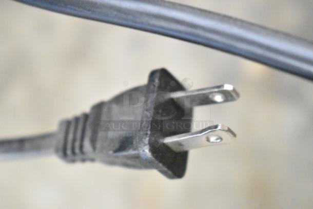 Close-up of a two-prong electrical plug attached to a power cable, associated with auctioned televisions.