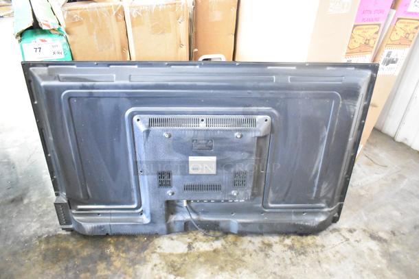 Back view of a Vizio television set among four TVs for auction, showcasing ports and labeling details. Buyer must pick up.