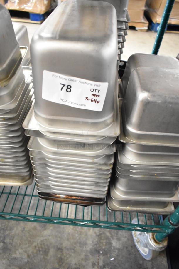 64 stainless steel drop-in bins, including 1/3 size, stacked on a shelf. Auction label reads "78, QTY x-64x."