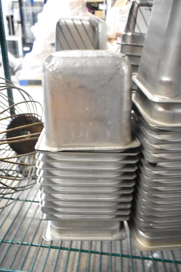 62 stainless steel drop-in bins, including 1/6 size, stacked on shelving with whisk attachment visible, for auction.
