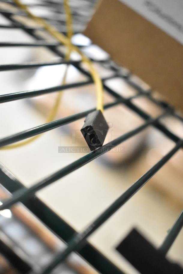 Close-up of a wire connector on a metal rack. Part of an auction for 8 new scratch and dent items, including Delfield 3516298 Coil Evaporator and Watts Safety Relief Valve.