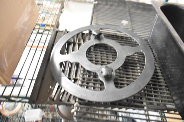 Six assorted items including a black ice head vent cover, on a metal rack. Condition: used. No visible labels.