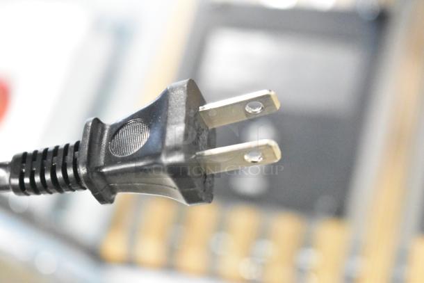 Close-up of a two-prong power plug on a blurred background.