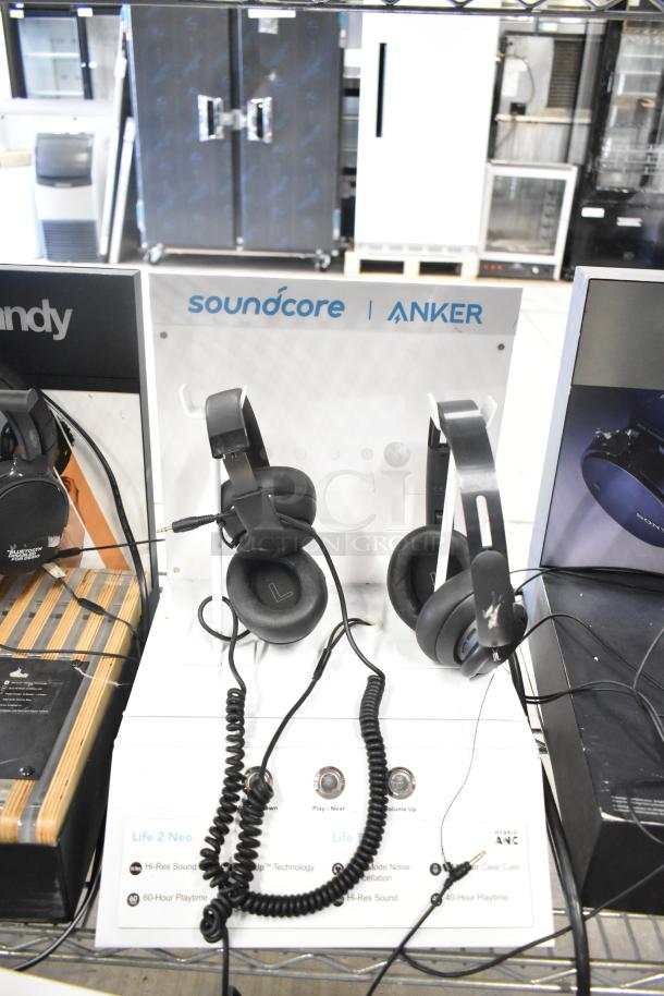 Auction display featuring Soundcore Anker headphones, including Life 2 Neo models on demo stands, highlighting Hi-Res sound and noise cancellation features.