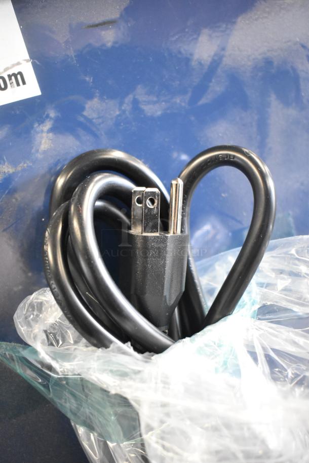 Black power cord coiled on blue background, partially wrapped in plastic, near a torn label. No visible store displays.