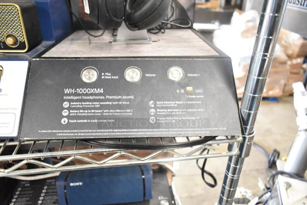 Store display with Sony WH-1000XM4 headphones, Skullcandy speakers, and Onn speaker, showcasing premium features.