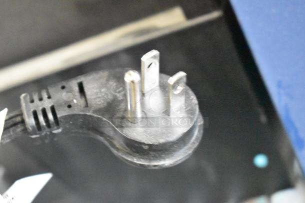 Sony headphones, Skull Candy speakers, and Onn speaker store displays. Power cord in focus, showing plug and wire detail.