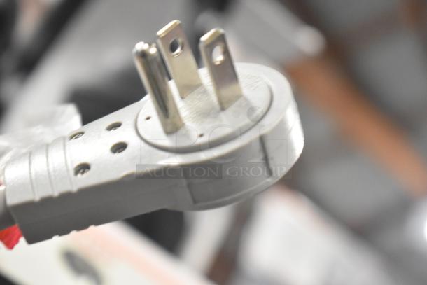 Close-up of a metal plug with three prongs, likely from a displayed electronic product, emphasizing its condition and design.