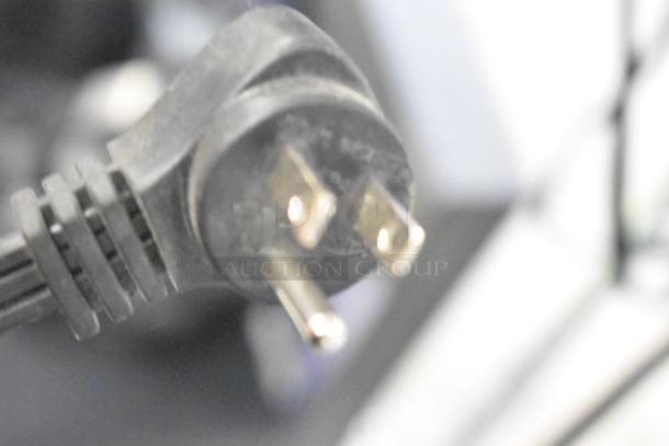 Blurry close-up of a three-pronged power plug, likely connected to one of the store display items.