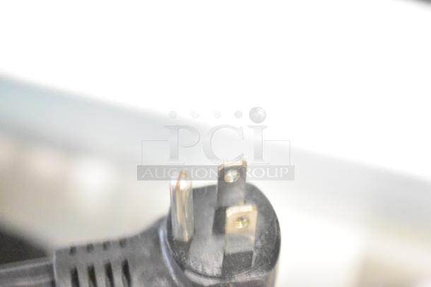Close-up of a three-prong power plug, likely for the store displays including a TonieBox, JBL speakers, and Altec speakers.