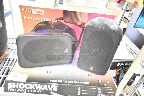 Three speakers on display including two JBL models and an Altec Lansing. Slight wear visible. Altec box with "Shockwave" branding.