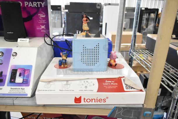 Four store display items, featuring a TonieBox with figurines, Anker Soundcore speaker, Onn speaker, and Sony speaker.