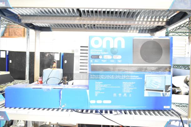 Set of four store display boxes: TonieBox, Anker Soundcore, Onn 2.1 Channel Soundbar System, Sony speaker. Each item is stacked on a shelf, highlighting the Onn packaging with specifications and features visible.