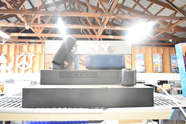 Four store display speakers including TonieBox 1, Anker Soundcore, Onn, and Sony. Good condition, branding visible.