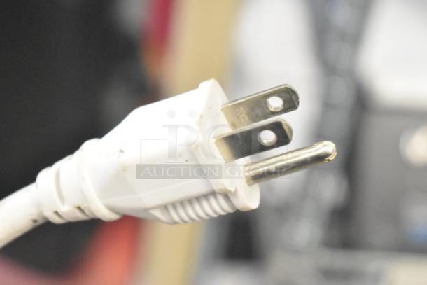 Close-up of a white electrical plug, slightly worn, with two metal prongs, part of store display items auction.