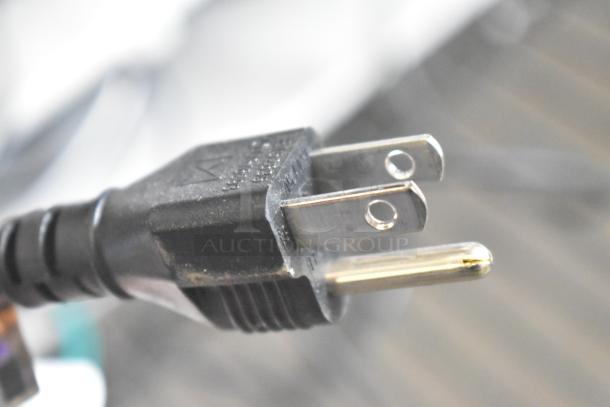 Close-up of a power plug showing a three-prong connection, black plastic casing, and metallic prongs.