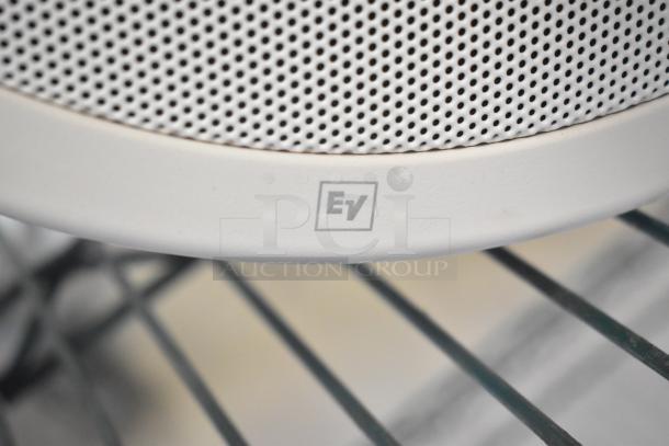Close-up of Electro-Voice EVID-P6.2UW speaker grille with "EV" logo. White finish, perforated design for sound quality.