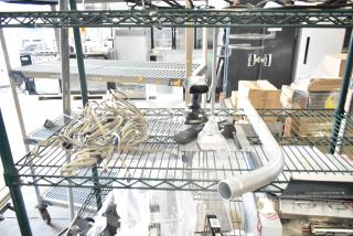 Lot of various items including metal handle, Motorola walkie talkie, barcode scanner, stand, wiring on metal shelf.