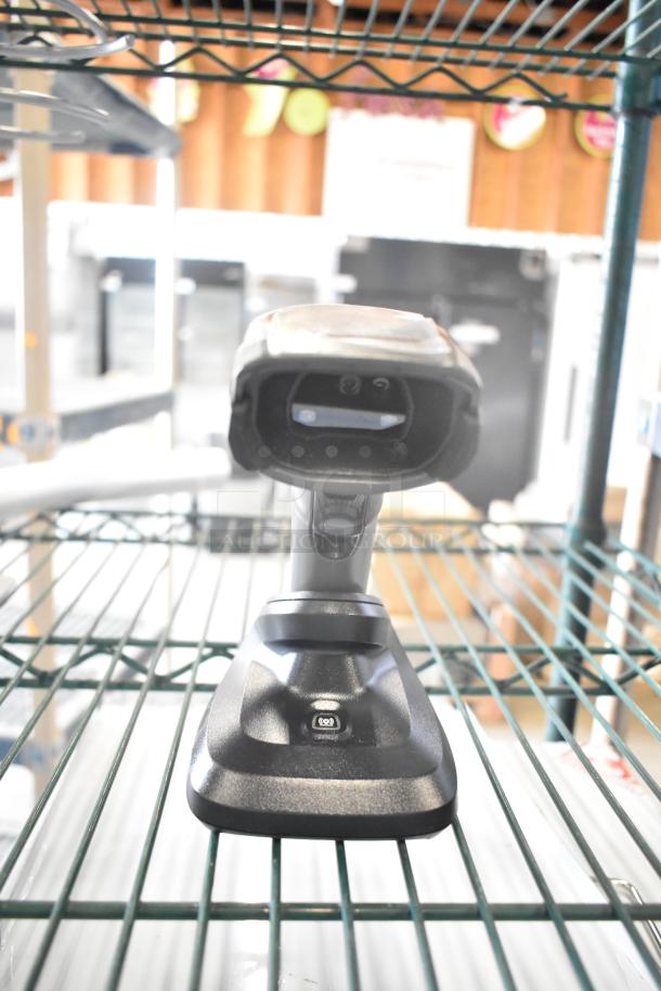 Lot including a barcode scanner with stand on a shelf. Part of a mixed item auction set with metal handle and Motorola walkie talkie.
