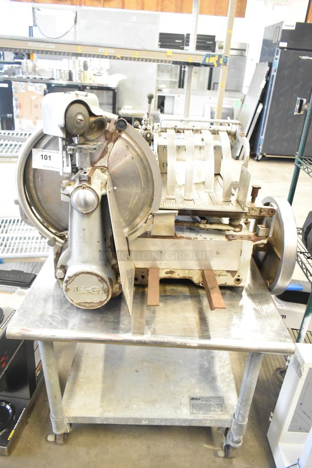 US Berkel commercial countertop flywheel meat slicer on equipment stand, showing signs of wear. Visible label: "US."