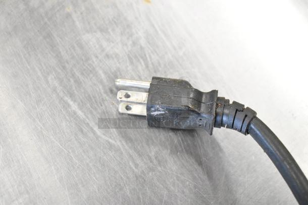 Sharp R-21LVF commercial countertop microwave plug, showing 120V connection. Black cord in used condition on metal surface.