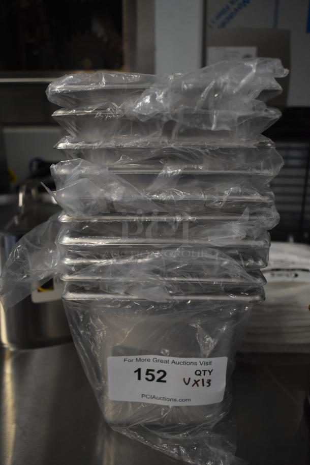 Stack of 13 brand new scratch and dent kitchen items, wrapped in plastic, with auction tag showing "152 QTY 13".