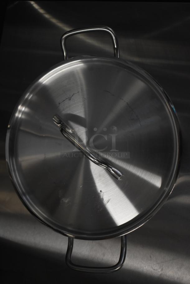 Stainless steel cookware lid with handles, minor scratches visible, part of a 13-piece scratch and dent kitchen item lot.