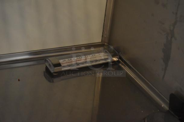 Thermometer inside the commercial salad prep table measuring internal temperature. Stainless steel interior visible.