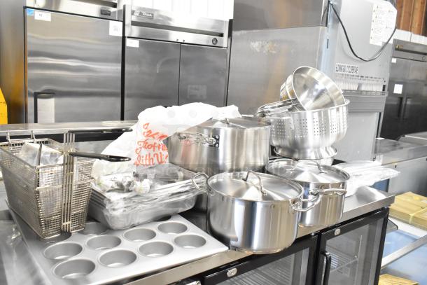 32 new kitchen items including China cap strainers, colander, muffin pan, fry baskets; some with scratches or dents.