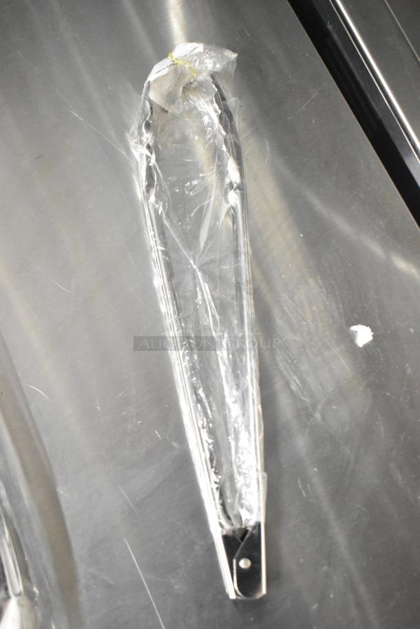 Brand new stainless steel kitchen tongs in plastic packaging, part of a scratch and dent auction.