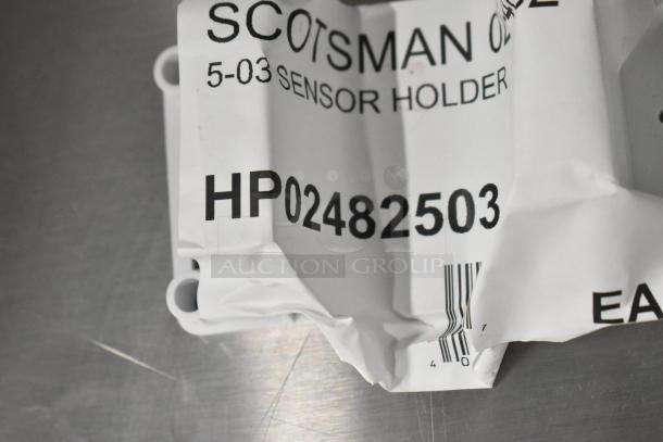 Scotsman sensor holder packaging with visible code HP02482503, slightly dented, on metal surface.