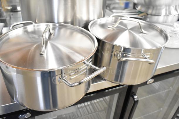 Stainless steel pots with lids, part of a 32-piece auction set, featuring brand new scratch and dent kitchen items.